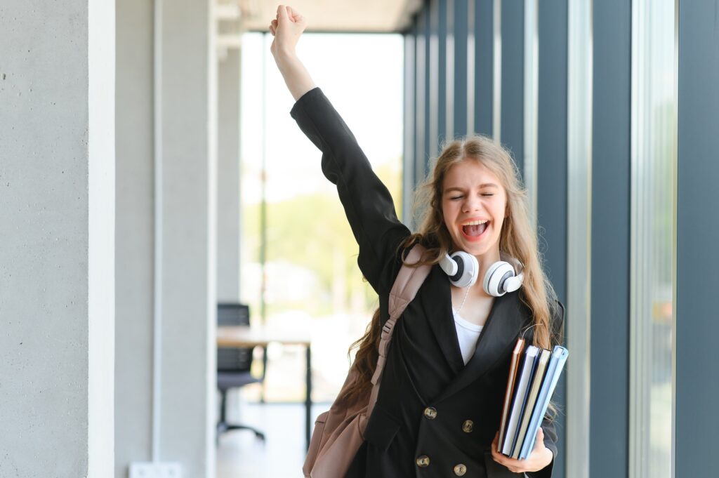 Emotional student girl within walls of institute celebrating successful exam pass,