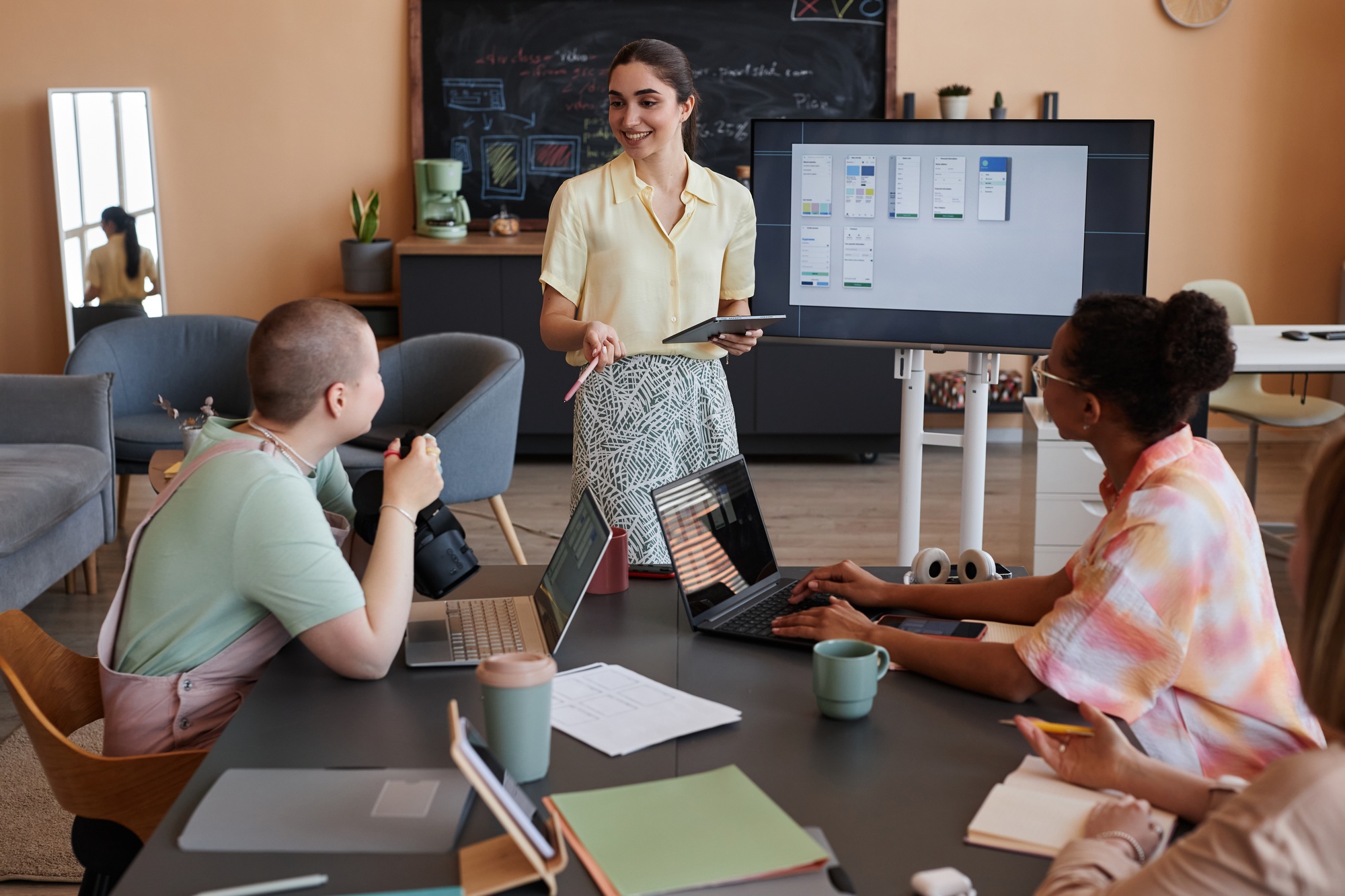 Smiling young woman leading meeting with all female team in office